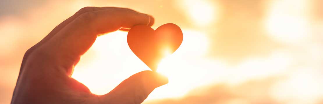 Hand holding a heart up to the sun
